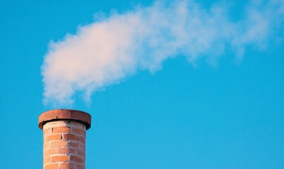 Smoke Rising From a Brick Chimney Against a Clear Blue Sky During a Sunny Day