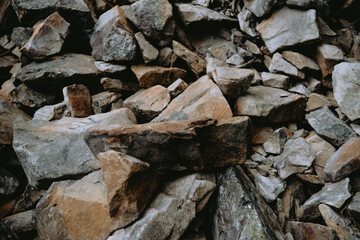 Rocky terrain with various sizes of stones scattered unevenly around a natural landscape backdrop during daylight hours
