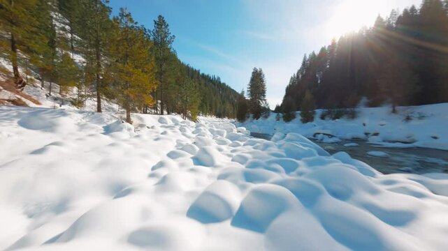 Flying low over a snowy fiver and snowy rocks on a cold winter morning