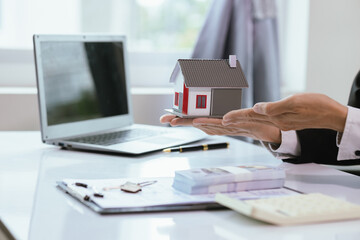 A real estate agent assists a client in buying a home, reviewing contracts, and signing mortgage documents. The process involves financial planning, property investment, and legal paperwork.