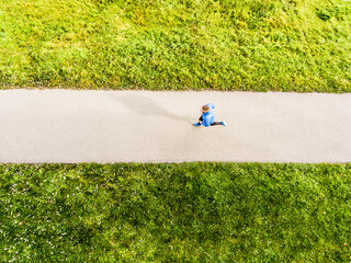 Fototapeta premium Aerial view of a runner running through autumn park on jogging path. Morning running training.