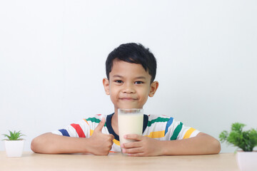 Asian little cute boy drinking milk. stays home with a smiling face, feels happy, and enjoys...