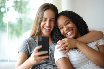 Interracial lesbian couple laughing checking phone