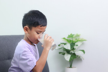 Asian little cute boy drinking milk. stays home with a smiling face, feels happy, and enjoys...