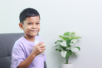 Asian little cute boy drinking milk. stays home with a smiling face, feels happy, and enjoys...