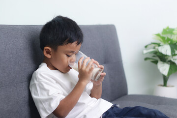Asian little cute boy drinking milk. stays home with a smiling face, feels happy, and enjoys...