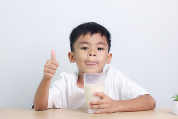 Asian little cute boy drinking milk. stays home with a smiling face, feels happy, and enjoys...