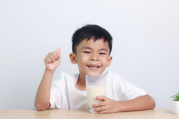 Asian little cute boy drinking milk. stays home with a smiling face, feels happy, and enjoys...