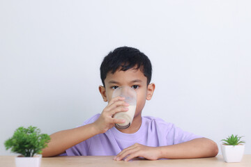 Asian little cute boy drinking milk. stays home with a smiling face, feels happy, and enjoys...