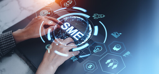 Hands typing on a laptop with SME hologram on a dark background. Concept of business and technology integration