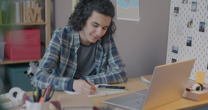 Intelligent teenager studying online with tutor speaking and writing looking at laptop screen focused on internet lesson at home. Virtual class and distance education concept.
