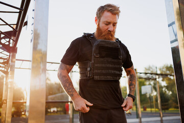 Bearded sportsman in weighted vest training in park in morning © Dmytro Hai