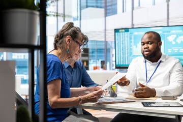 Senior person signs the financial investment contract during a discussion with a banker, retirement planning and protecting savings. Client agreeing with terms for the pension option.