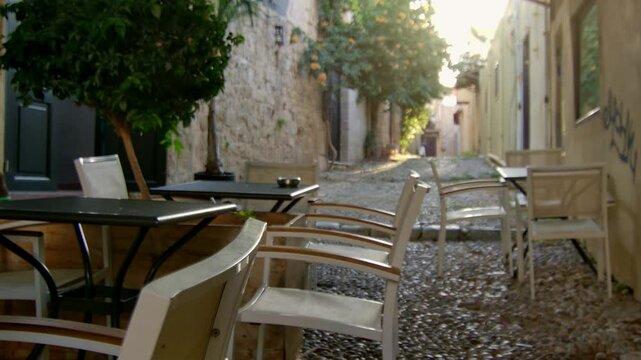 SOme empty chairs by an empty , quite street in Rhodes.