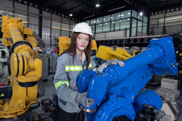 Engineer standing by robotic arm and operating machine in industry factory, technician worker check for repair maintenance electronic operation