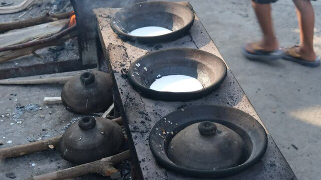 Traditional Indonesian pancake "serabi" cooking in a clay pan over a wood fire. The crispy edges and soft center reflect the authentic, rustic preparation of this popular street food delicacy.