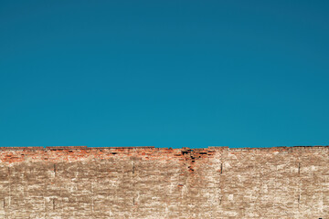 Old ruined brick wall beneath the clear blue sky