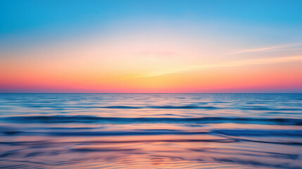 Obraz premium Tranquil Summer Sunset Over Ocean, a serene and warm evening view featuring blurred hues of orange and pink merging with the gentle waves of the sea.