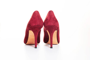Close up of red high heel shoes on white background. Female stiletto heels in suede leather, back...