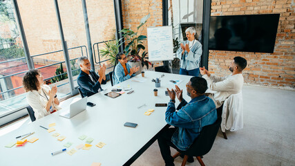 Diverse team giving applause during a project presentation in a sleek, stylish conference room