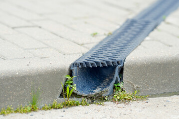 Channel drain system with plastic grate on paved road. Stormwater management. Durable plastic...