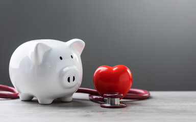 white piggy bank, a stethoscope, and a red heart are placed on a table. The image symbolizes the connection between financial planning, health care, and well-being.