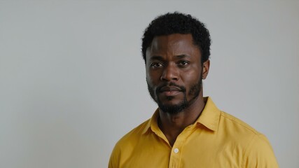 Obraz premium adult black hair subsaharan african man in yellow shirt model portrait standing straight on a plain white background for ad concept space for text