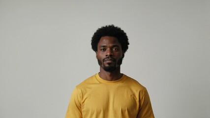 Obraz premium adult black hair subsaharan african man in yellow shirt model portrait standing straight on a plain white background for ad concept space for text
