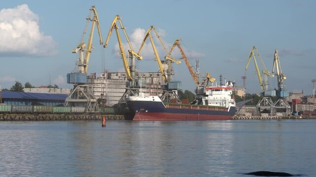 Large cranes in the port, cranes are unloading coal from railway wagons to a cargo ship to send it for export. Operation of cranes in the seaport. High quality 4k footage