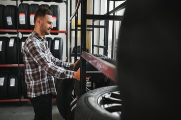 Portrait young man customer examining brand and product characteristics while buying new tires in auto department of dealership.