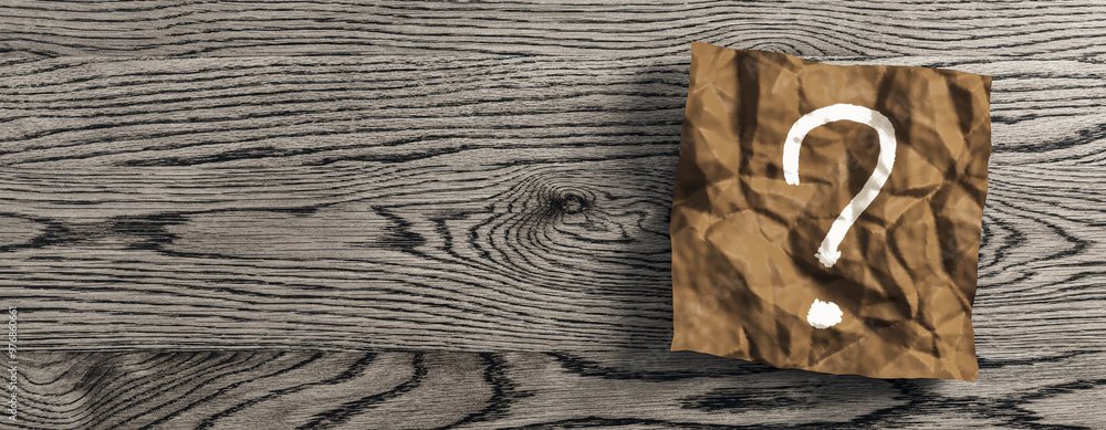 Poster close up of wrinkled brown piece of paper with question mark on wide wooden desk background with moc
