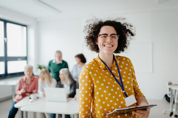 Portrait of teacher with seniors attending computer and technology education class. Digital...