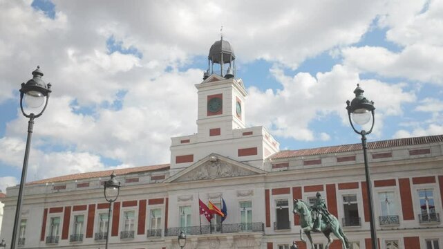 Close up shot of Casa de Correos facade Regional Government of Madrid (Old Post Office Building) and Carlos III Statue on a Sunny summer day blue sky and white cloud Puerta del Sol in Madrid, Spain