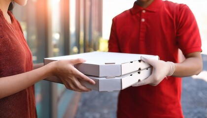 Delivery person in red shirt handing pizza boxes to a customer.