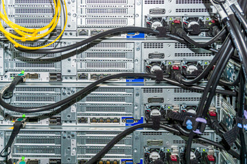 Back side of the network servers with ethernet and power cables  in the rack. Power supplies with fans are visible