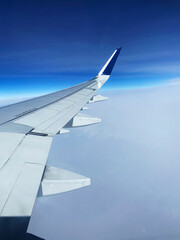 Obraz premium Airplane wing flying above the clouds on sunny day