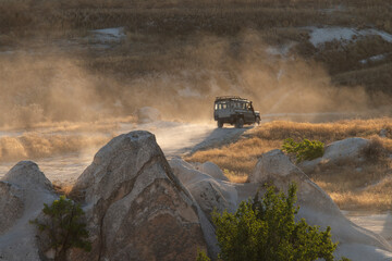 In Cappadocia, at sunset, there is a stunning view of the valley, along which a jeep is driving, raising clouds of dust behind it.Turkey © Elena
