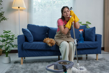 Tired Asian housewife after doing housework, home office, sitting on the floor in living room near...
