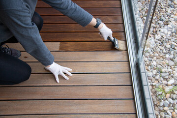 Wood floor sealing and varnishing, hand holding a brush applying transparent protective coat