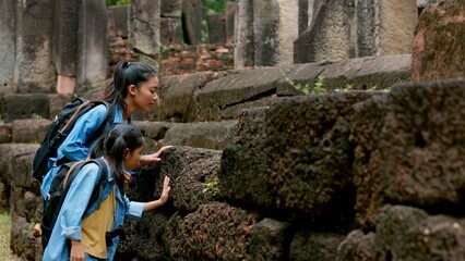 Two Asian siblings explore the Phnom Wan Stone Castle, admire the ancient architecture and take photos to record their memories.