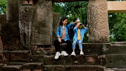 Two Asian siblings explore the Phnom Wan Stone Castle, admire the ancient architecture and take photos to record their memories.