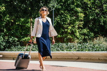 Confident Woman Walking with Suitcase in Urban Park