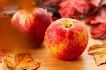 Ripe organic red apple, leaves, on wooden table background. Autumn composition.