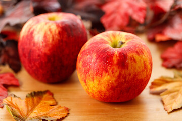 Ripe organic red apple, leaves, on wooden table background. Autumn composition.