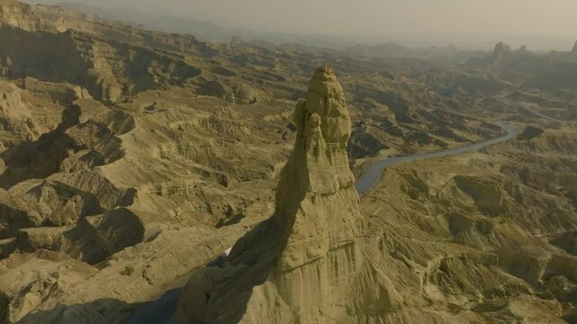 Aerial view of the Makran Coastal Highway in Balochistan, Pakistan, featuring winding roads through dramatic rocky landscapes under a clear sky. Orbit Motion