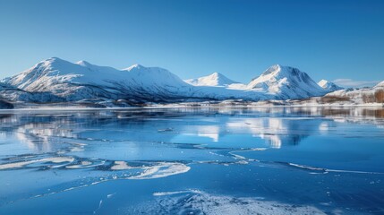Naklejka premium A stunning snowscape showing a frozen lake surrounded by snow-capped mountains, with a clear blue sky reflecting off the ice.
