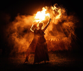 The enchanting fire dancers beautifully showcase their talent with fascinating flames during the performance.