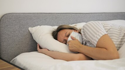 A woman suffering from flu lies in bed looking weak and tired. Her illness is evident through her facial expression and body language Video highlights struggle with illness, showing impact of disease - Powered by Adobe