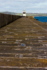 View along the last section of the Holyhead Breakwater Victorian promenade towards the Grade II Listed lighthouse at the tip of the structure, Holy Island, Anglesey, Gwynedd