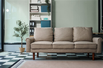 A cozy interior with soft lighting, featuring a stylish sofa, glass-walled room, and neatly arranged shelf. The carpet complements the design, creating a warm and inviting space with no people.